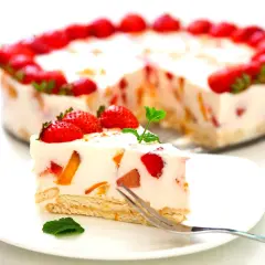 Pyszne ciasto z truskawkami bez pieczenia na herbatnikach, ozdobione świeżymi owocami i miętą. Idealne na letnie popołudnie.
