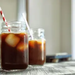 Dwie szklanki z uchem, wypełnione kawą z lodem i słomkami. Idealna nazwa dla tego orzeźwiającego napoju to kawa z lodem.