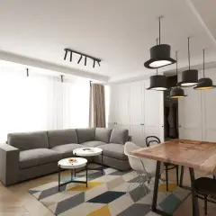 Nowoczesny salon z szarą kanapą, stolikami kawowymi i stołem z litego drewna. Inspiracja, jak umeblować salon, by był funkcjonalny i stylowy.