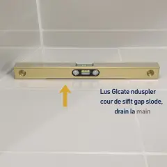 Niveau à bulle doré sur carrelage blanc, vérifiant la pente de la canalisation de la salle de bain pour un bon drainage.