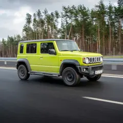 Jaskrawozielony suzuki jimny 5-drzwiowy na drodze. Sprawdź suzuki jimny 5-drzwiowy cena i możliwości.