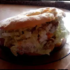 Pyszny kebab w bułce z chrupiącą sałatą i kremowym sosem, gotowy do zjedzenia.