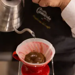 Versando acqua calda su caffè macinato in un filtro di carta rosso, per preparare un caffè filtro. Ecco come funziona la caffettiera americana.