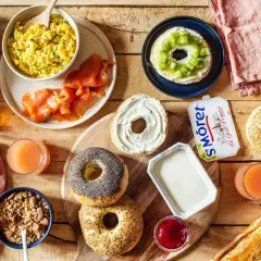 Un petit déjeuner peu calorique avec œufs brouillés, saumon fumé, bagels, fromage frais, fruits et jus.