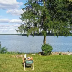 Osoba odpoczywa nad jeziorem, ciesząc się spokojem. To jedno z tych magicznych miejsc Kujawsko-Pomorskiego, gdzie czas płynie wolniej.