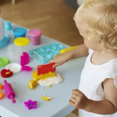 Mała blondynka w żłobku tworzy cuda z plasteliny. Wesołe zabawy sensoryczne rozwijają jej kreatywność.