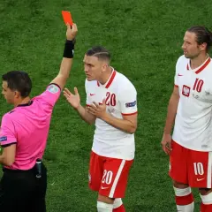 Sędzia pokazuje czerwoną kartkę, co oznacza koniec gry dla zawodnika.