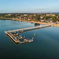 Molo w Mechelinkach z łodziami i widokiem na plażę i zabudowania. To świetne mechelinki atrakcje dla każdego.