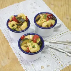 Drei Tassen mit Tortellini-Salat, garniert mit frischen Kräutern. Perfekt für die **10 besten Salate** zum Sommerfest.