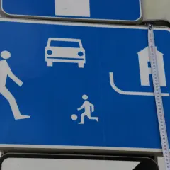 Znak D18: strefa zamieszkania z pieszym, dzieckiem bawiącym się piłką, samochodem i domem.
