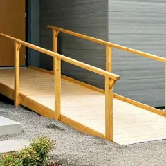 Eine stabile Holz-Rollstuhlrampe, die man selber bauen kann, mit Geländer führt zur Haustür.