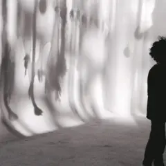 Chłopiec z gitarą, w cieniu, na tle rozmytych kształtów. "Boys don't cry" - jego muzyka mówi wszystko.