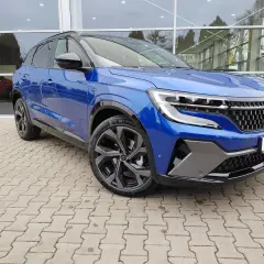 Niebieski Renault Austral prezentuje swoje imponujące wymiary na tle salonu samochodowego. Elegancki SUV z dynamiczną linią.