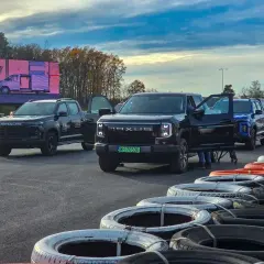 Kolekcja nowoczesnych pickupów Maxus, w tym czarny model z otwartymi drzwiami, ustawiona na torze wyścigowym.