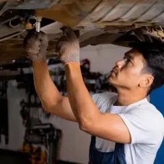Mécanicien travaillant sous une voiture, cherchant la source d'un bruit butée embrayage.