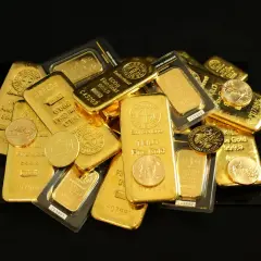 Stos sztabek złota, w tym sztabka złota 100 gram, oraz złote monety, błyszczące na czarnym tle.