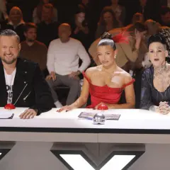 Trzy osoby siedzące przy stole jurorskim, w tym dwie kobiety w sukniach i mężczyzna w czarnej kurtce.
