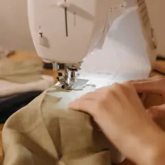 Hands guide fabric through a sewing machine, a peaceful scene of a sewing hobby.