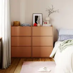Modernes schlafzimmer design mit orangefarbenen Kommoden, einem Bett mit gestreiften Kissen und einer grünen Decke.