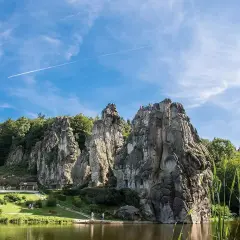 Felsformationen am Wasser, umgeben von grünen Bäumen, ein Ort, der an magische Orte in Deutschland erinnert.