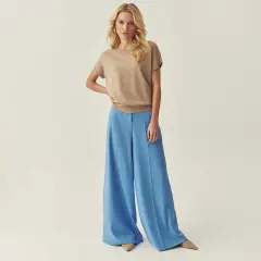 Elegancka stylizacja: beżowy sweterek i błękitne spodnie z wysokim stanem. Idealne połączenie, by zadać sobie pytanie: jaka bluzka do spodni z wysokim stanem?