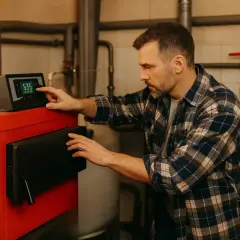 Mężczyzna ustawia panel sterowania pieca gazowego, przygotowując go do letniego postoju.