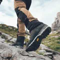 Turysta stawia kroki na kamienistym szlaku, jego buty z podeszwami Vibram zapewniają pewność na nierównym terenie.