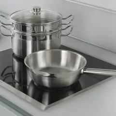 Pentole e padelle in acciaio inox pronte per cucinare su piastra a induzione.