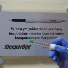 Dłoń w niebieskiej rękawiczce trzyma urządzenie do znieczulania komputerowego SleeperOne.