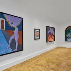 Gallery wall featuring surreal artworks by Alexandria Smith, including a purple figure by a brick archway and abstract forms.
