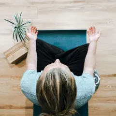 Osoba siedzi w pozycji medytacyjnej na macie. To idealny moment, by zacząć medytację mindfulness.