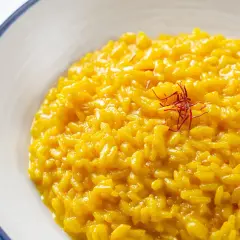 Risotto alla Milanese, un classico tra i piatti tipici lombardi, cremoso e profumato allo zafferano, guarnito con pistilli rossi.