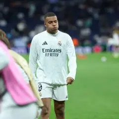 Mbappé, młody piłkarz Realu Madryt, w białej koszulce treningowej z logo Emirates.