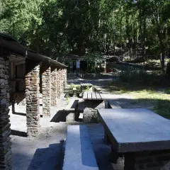 Merendero Laujar, un lugar ideal para disfrutar de un picnic rodeado de naturaleza. Mesas de piedra y madera bajo un techo rústico.