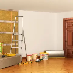 Materiali per isolamento termico e acustico, inclusi rotoli di lana minerale per un efficace cappotto interno antimuffa. Attrezzi da lavoro e pannelli pronti per l'installazione.