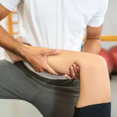 Fizjoterapeuta masuje udo pacjenta, pomagając w rehabilitacji po złamaniu nogi.