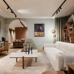 Un salon à la décoration épurée, avec un canapé blanc texturé, une étagère en bois géométrique et des œuvres d'art modernes.