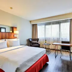 Przytulny pokój w hotelu Radisson Blu Scandinavia Hotel Dusseldorf z wygodnym łóżkiem, fotelem i biurkiem.