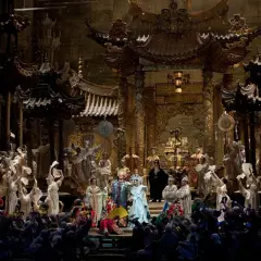 Scen från operan Turandot med en storslagen kinesisk palatsmiljö och många skådespelare i färggranna dräkter.