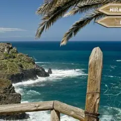 Cartel indicador en el sendero rambla de castro, señalizando Mirador S. Pedro y La Casona, con el mar azul de fondo.