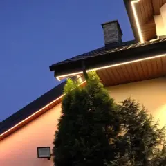 Eleganckie oświetlenie w podbitce domu, rozmieszczone co kilka metrów, tworzy ciepłą atmosferę wieczorem.