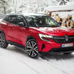 Czerwony Renault Austral na śniegu, z widocznymi felgami i grillem. Poznaj jego wymiary i możliwości w zimowych warunkach.