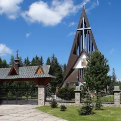 Nowoczesny kościół na Bachledówce z charakterystyczną, strzelistą wieżą i drewnianym zadaszeniem bramy wjazdowej.
