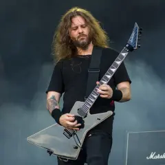 Charyzmatyczny gitarzysta rockowy z długimi włosami, grający na czarnej gitarze typu explorer. Jeden z wielu utalentowanych polskich gitarzystów rockowych.