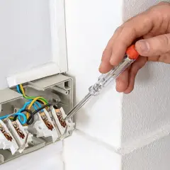 Ręka trzyma próbnik napięcia, sprawdzając instalację elektryczną. Tak działa próbnik napięcia, pomagając w bezpiecznym montażu.