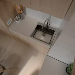 Nowoczesny zlew kuchenny podblatowy ze stali nierdzewnej, idealnie wkomponowany w blat. Obok moździerz i drewniane akcesoria.