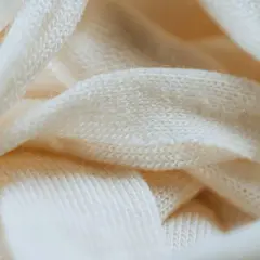 Miękka, kremowa wełna w zbliżeniu. Delikatne włókna tworzą splot, który może pomóc w zrozumieniu, jak skurczyć wełnę.