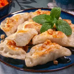 Pyszne pierogi ruskie przepis babci, okraszone skwarkami i udekorowane miętą.