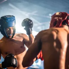 Two boxers spar, their faces determined as they engage in a fierce fight within the ring.