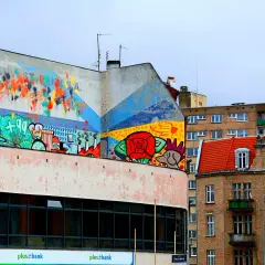 Kolorowy mural na budynku, pełen symboli i abstrakcji, to przykład tego, czym jest postmodernizm w sztuce miejskiej.